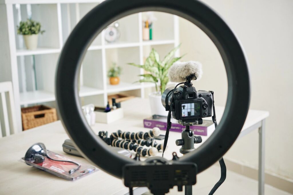 Circle lamp, digital camera and monopods in office of professional blogger.