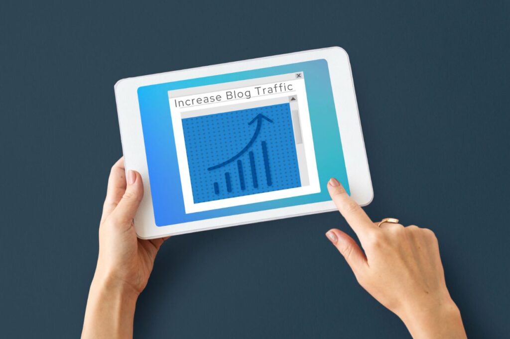 A person holding a tablet displaying a screen with the text "Increase Blog Traffic" and an upward trending graph, symbolizing growth in website visits.