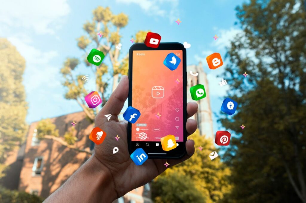 A hand holds a smartphone displaying social media icons floating around it, symbolizing the power of digital marketing and social media engagement in growing a blogging business.