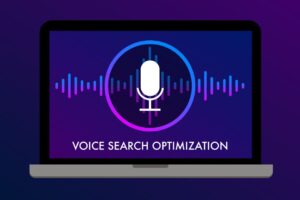 Illustration of a laptop screen displaying a microphone icon within a circular outline, surrounded by soundwave graphics in gradient shades of purple, blue, and pink. Below the icon, the text reads 'Voice Search Optimization' on a dark purple background.